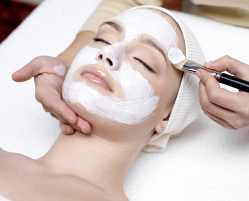 Woman receiving facial mask at beauty salon